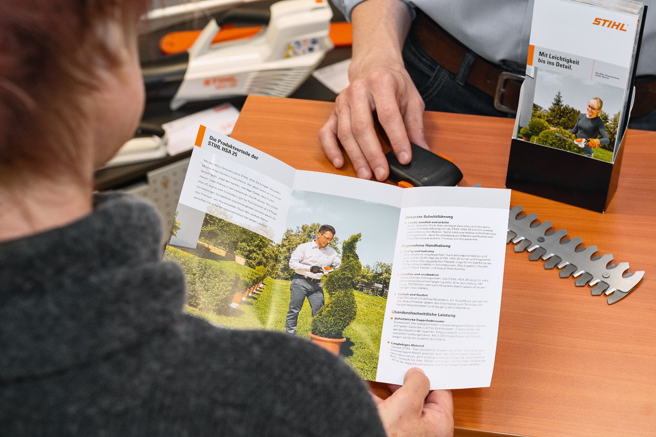 Osoba przygląda się zaletom produktu STIHL HSA 25 w broszurze