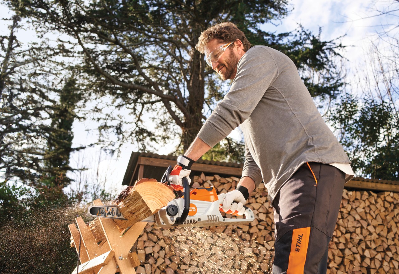 Mężczyzna używający STIHL MSA 70 do cięcia drewna w ogrodzie