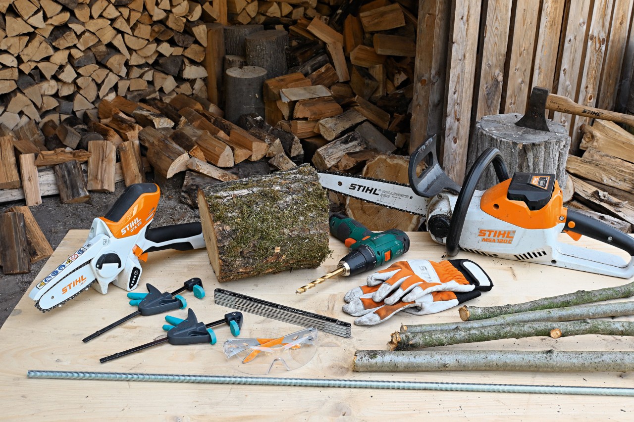 Materiały i narzędzia do samodzielnego wykonania drewnianej choinki, w tym akumulatorowa pilarka łańcuchowa STIHL MSA 120 i akumulatorowa przecinarka STIHL GTA 26