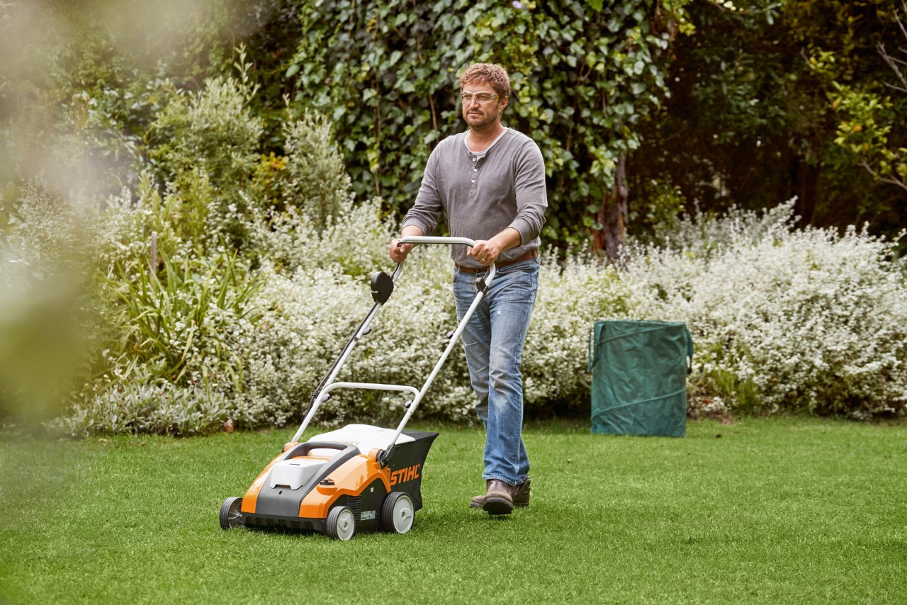 A man scarifying a green lawn with a STIHL RLA 240 cordless lawn aerator
