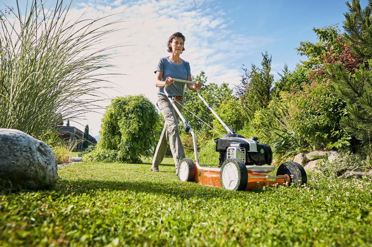 Kobieta używająca spalinowej kosiarki do mulczowania STIHL RM 2 R na zielonym terenie