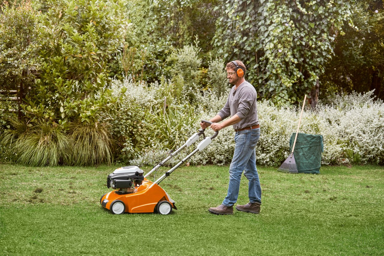 Mężczyzna wertykuluje zielony trawnik wertykulatorem STIHL RL 540