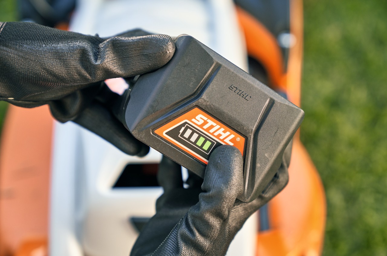 Akumulator litowo-jonowy STIHL, w tle kosiarka akumulatorowa STIHL RMA 339 C
