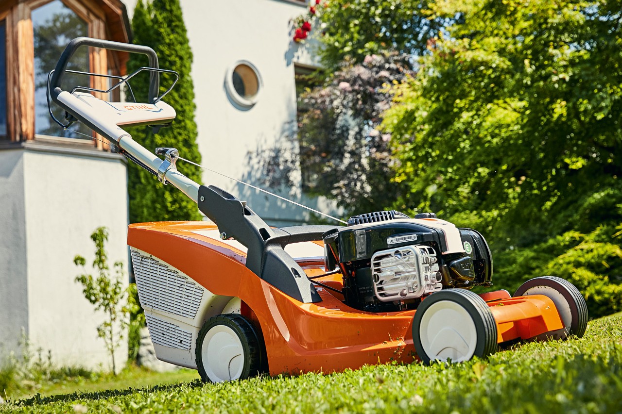 Benzynowa kosiarka STIHL RM 443 T na zielonym trawniku przed domem 