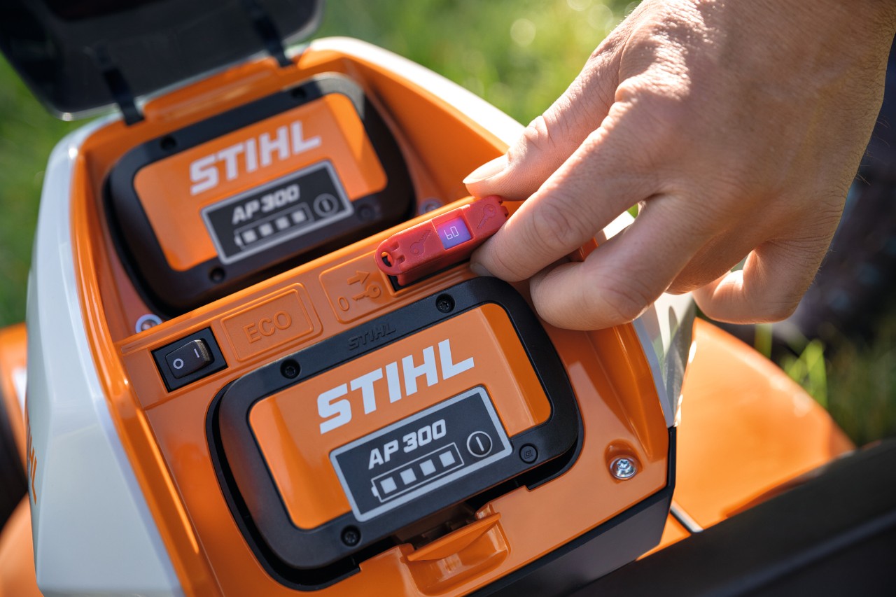 Osoba wkłada wtyczkę bezpieczeństwa do kosiarki akumulatorowej STIHL RMA 448 VC 