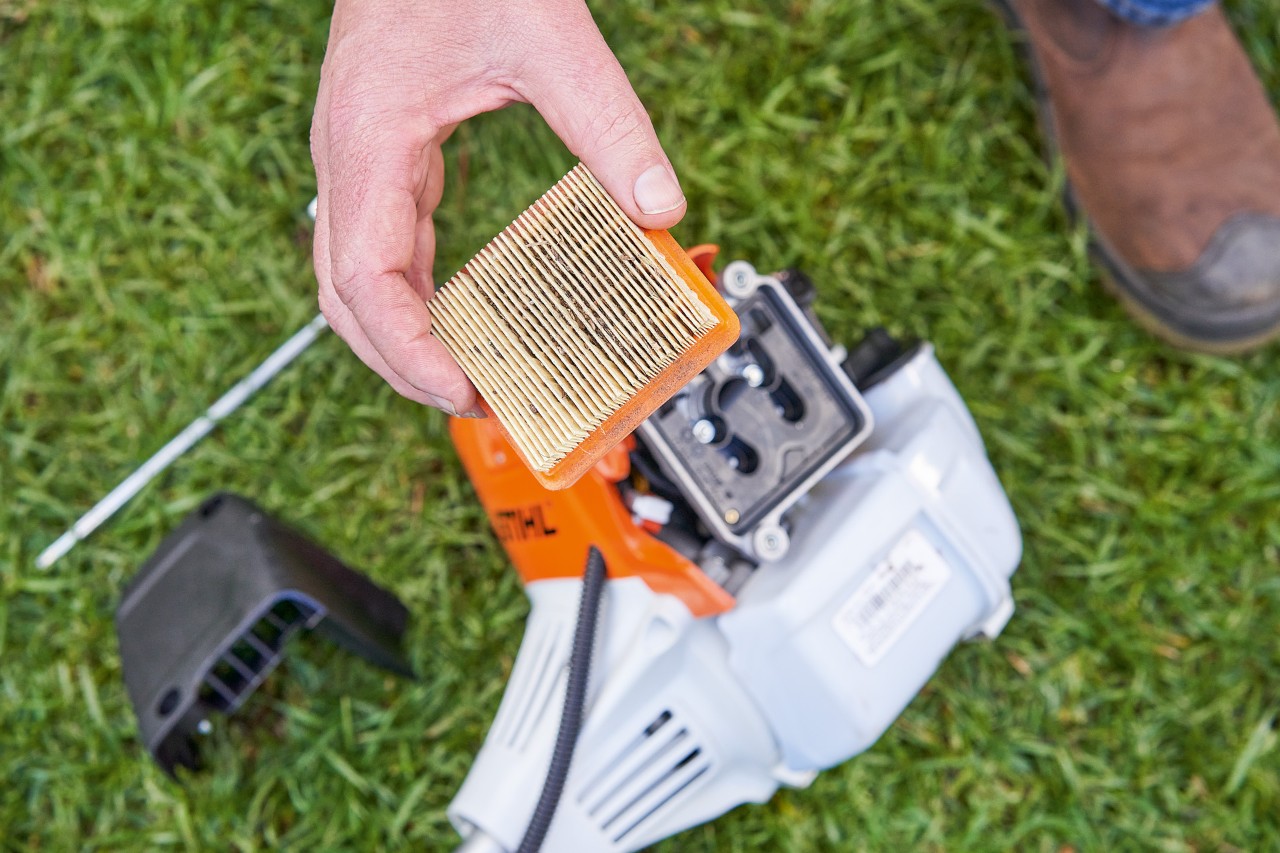 Osoba wyjmuje filtr powietrza z kosy mechanicznej STIHL w celu jego wyczyszczenia 