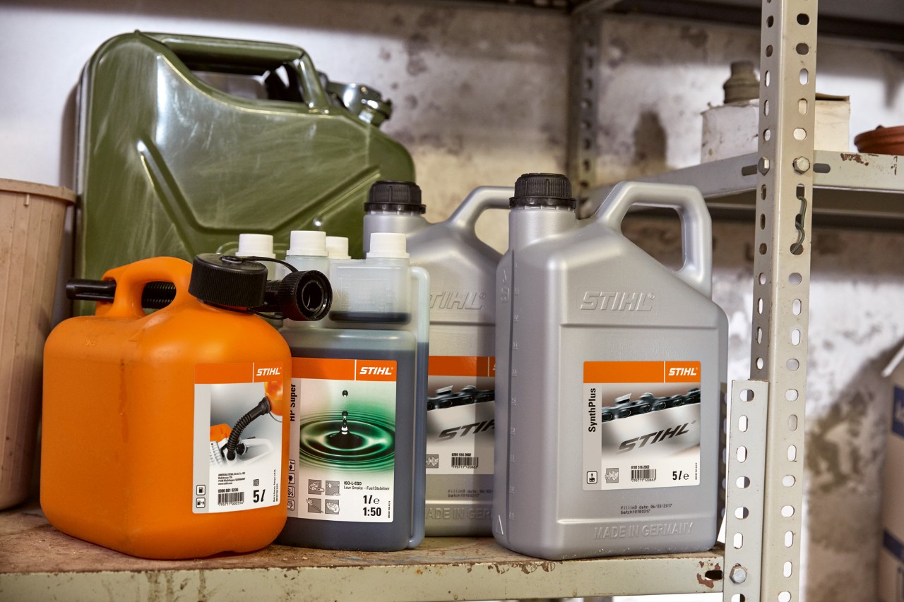 Jasny kanister z olejem do silników dwusuwowych STIHL HP Super i pomarańczowy kanister z mieszanką paliwa do kosy mechanicznej