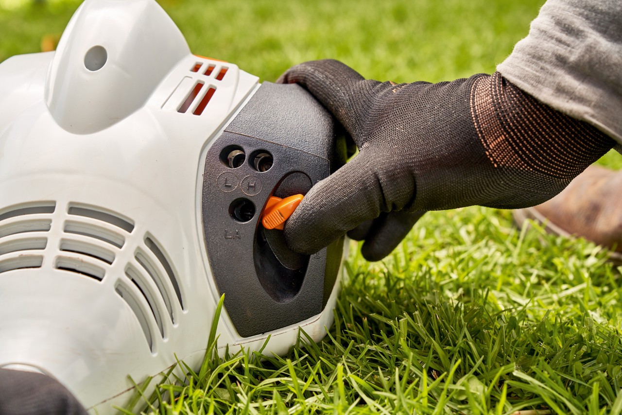 Mężczyzna ustawia dźwignię benzynowej kosy mechanicznej STIHL FS 56, aby ją uruchomić