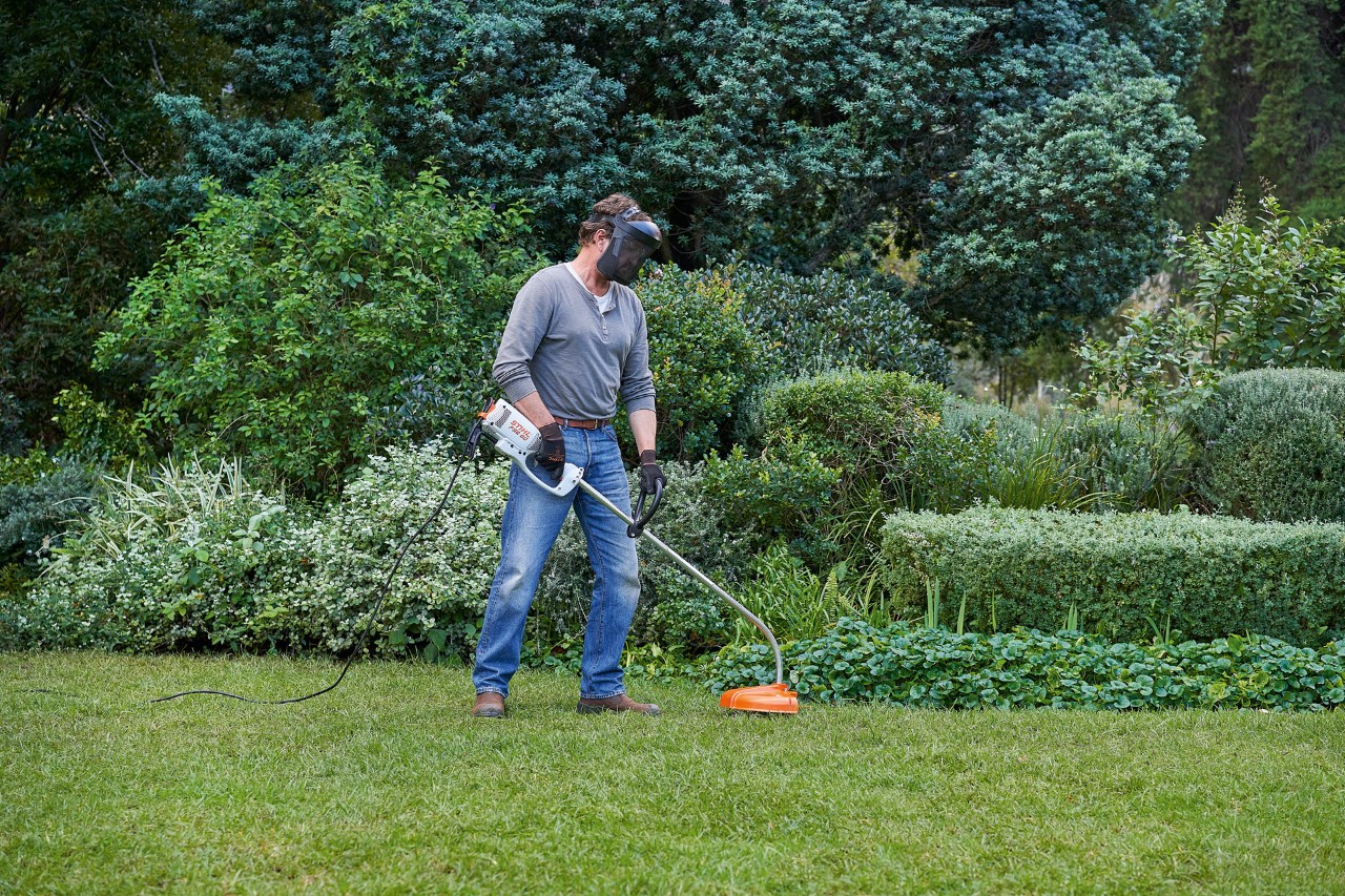 Mężczyzna z elektryczną kosą mechaniczną STIHL FSE 60 stoi stabilnie