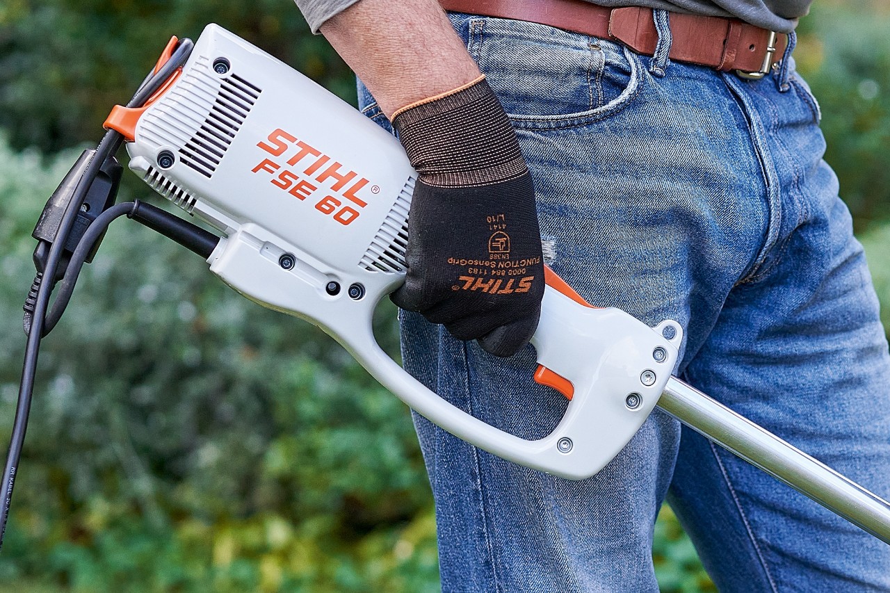 Mężczyzna naciska przełącznik, aby wyłączyć elektryczną kosę mechaniczną STIHL FSE 60.