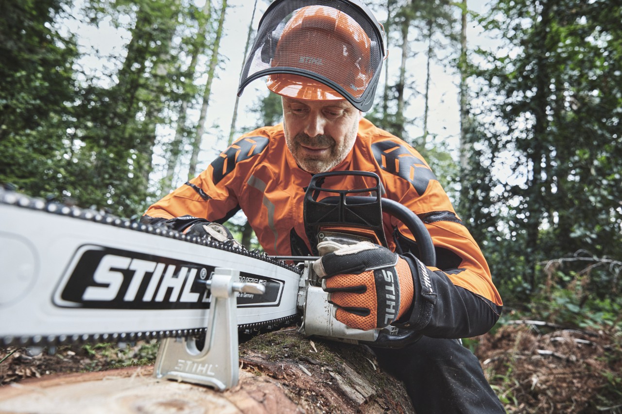 Mężczyzna w odzieży ochronnej pracuje z pilarką spalinową STIHL w lesie